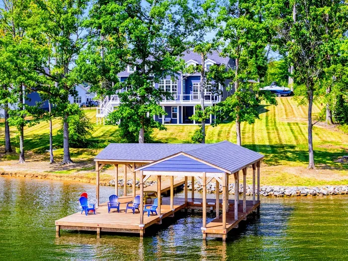 Waterfront View - The Shoreline sits on a private wooded lot with a covered dock gazebo and colorful Adirondack seating at the water's edge.