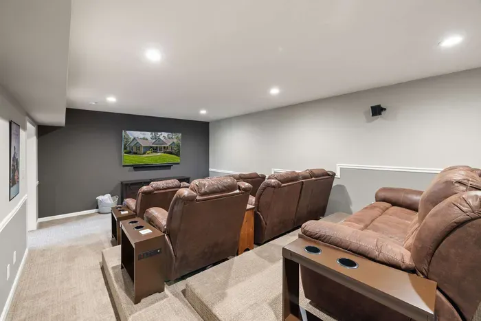 A cozy home theater with tiered seating, plush recliners, and a convenient bar area, perfect for movie nights and entertaining guests.