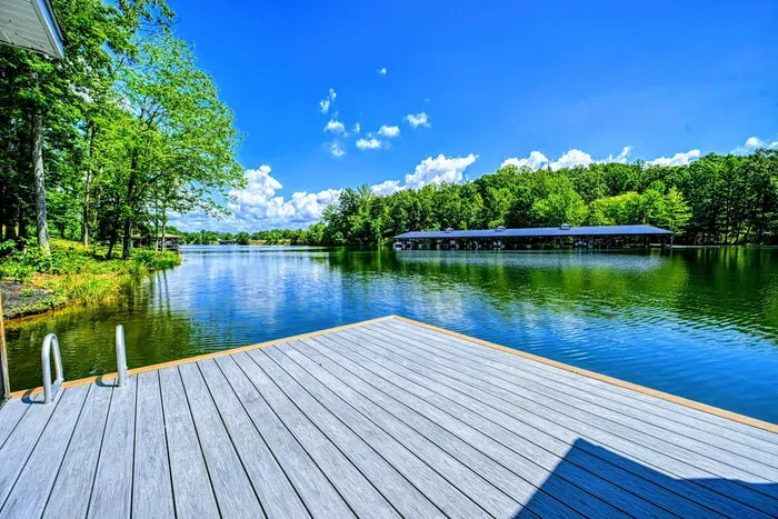 Dock and Lake View - The composite dock extends into crystal-clear water with a swim ladder, open lake views, and blue skies overhead.