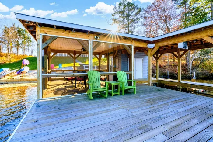 Lakeside dock with a screened-in seating area and Adirondack chairs, perfect for relaxing by the water