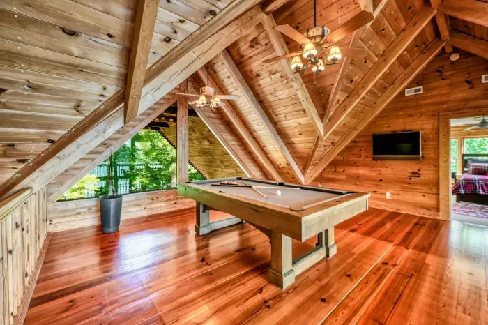 A stylish and airy loft combines modern amenities like a TV with the rustic charm of natural wood and a pool table.