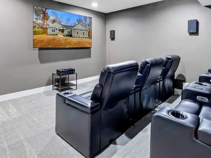 Enjoy a cozy and modern home theater experience with plush recliner seating and a large wall-mounted screen in this entertainment room.