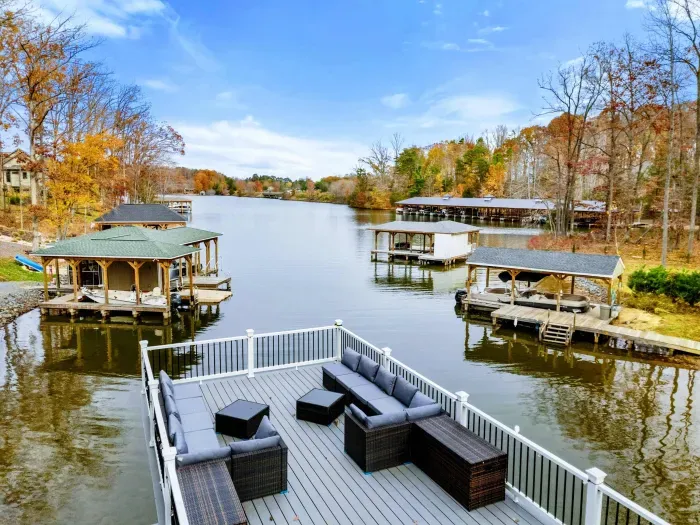 Spacious outdoor deck with comfortable seating, lounge chairs, and scenic views of a wooded area and water.