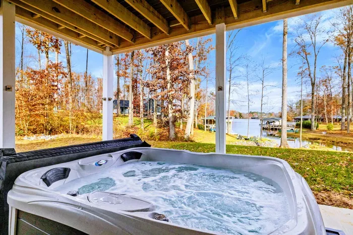 Relaxing hot tub on a covered patio with beautiful views of the lake and surrounding wooded area.