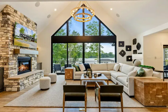 Great Room - A soaring, design-forward space where comfort meets lakefront beauty, anchored by a stone fireplace and gold chandelier.