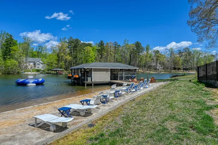 Shoreline - Private sandy beach with lounge chairs lined along the water, dock and trampoline just steps away.