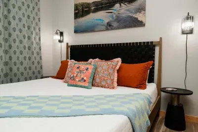 Kick back in the Whatever Rows Your Boat suite featuring lake photography by Jessica Fike and painterly details by Colleen DuBose. The woven leather headboard and mix of patterns make this king retreat equal parts cozy cabin and boutique stay