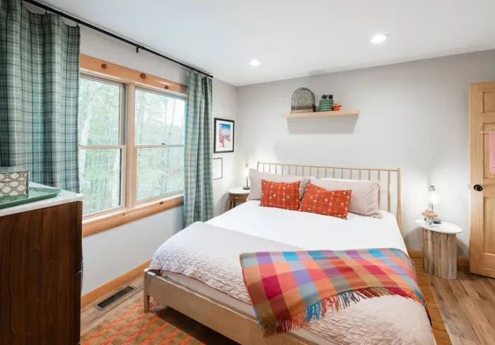 Morning light filters through plaid curtains and pink accents in “Ski Bunny’s Boutique.” Soft textures, playful color, and a touch of whimsy make this room feel like a gentle pause between mountain adventures.