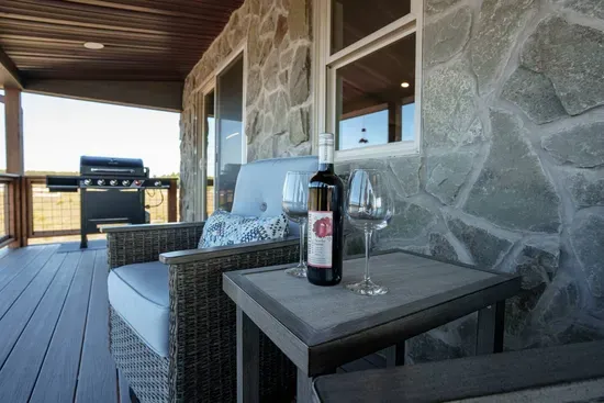 The expansive covered deck has 4 premium chairs with a large gas grill.