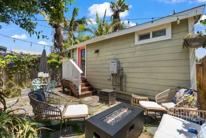 Relaxing backyard oasis with cozy seating, a fire pit, and string lights—perfect for laid-back evenings under the palm trees.