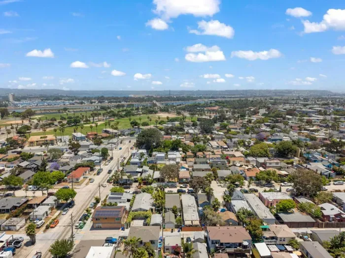 Scenic aerial view of Ocean Beach with lush palms, charming homes, and sparkling bay waters in the distance.