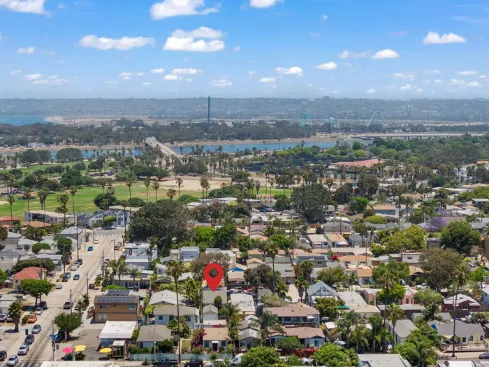 Scenic aerial view of Ocean Beach with lush palms, charming homes, and sparkling bay waters in the distance.