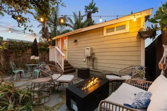 Relaxing backyard oasis with cozy seating, a fire pit, and string lights—perfect for laid-back evenings under the palm trees.