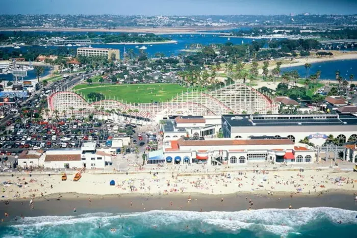 Aerial view of Mission Beach showcasing the boardwalk, sandy shoreline, and the iconic Belmont Park with its seaside roller coaster.