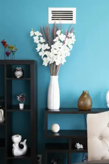 This setup gives a modern and clean aesthetic, combining a striking wall color with contrasting black furniture and white, brown, and colorful accents.