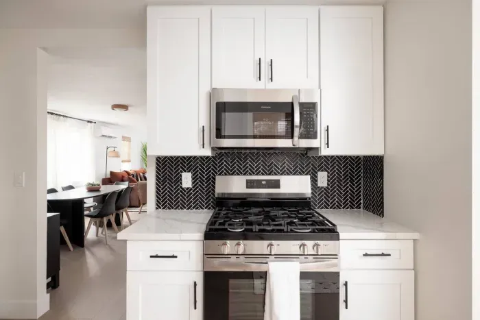 Modern kitchen with stainless steel stove and microwave, sleek backsplash, and plenty of space to cook.