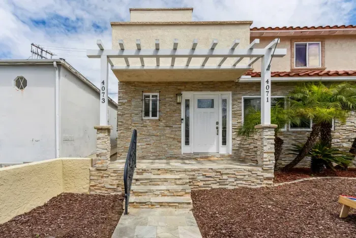Welcoming stone entryway with a modern pergola and inviting front steps.