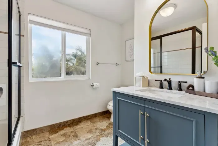 Chic bathroom with navy vanity and gold accents.