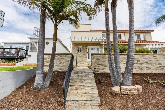 Stone pathway lined with palms leading to the welcoming front entrance.