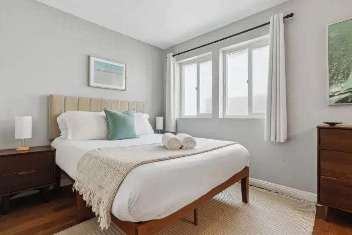 Sunlit roomy queen-sized bed with clean white design.