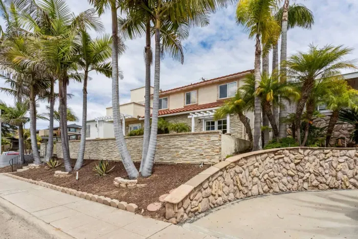 Corner view of the home framed by tropical palm trees.