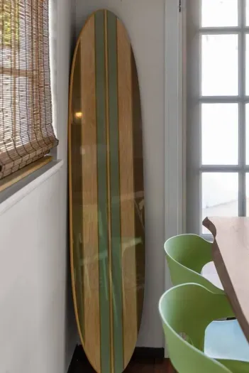 Polished surfboard leans near bamboo blinds and chairs