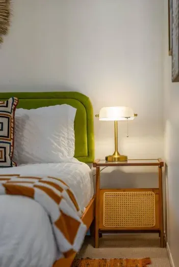 Brass lamp glows beside bold geometric bedding