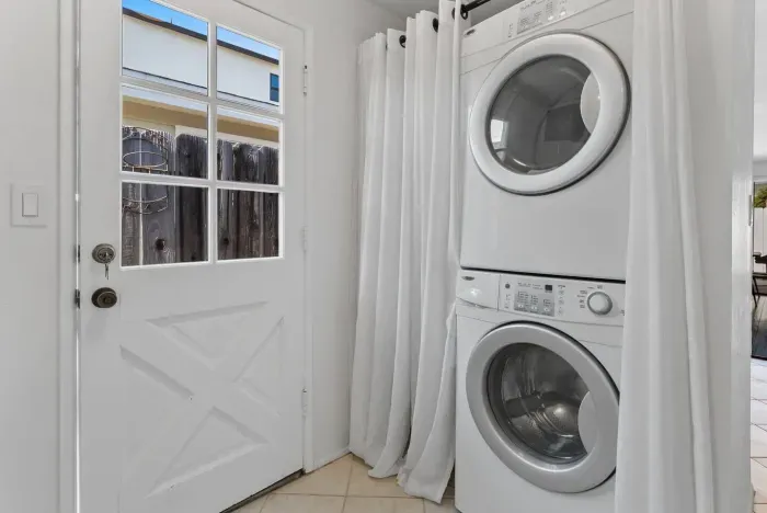 White curtain hides stacked washer and dryer nook