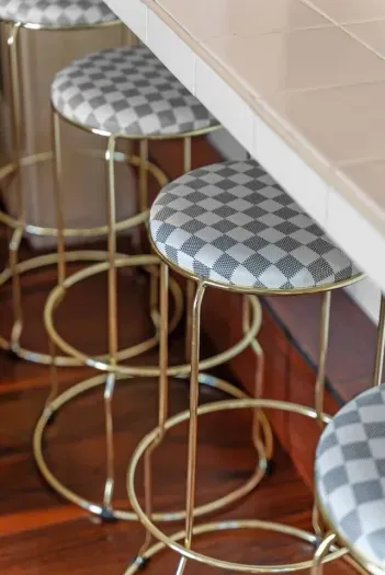 Patterned stools gleam beneath brass bar legs

