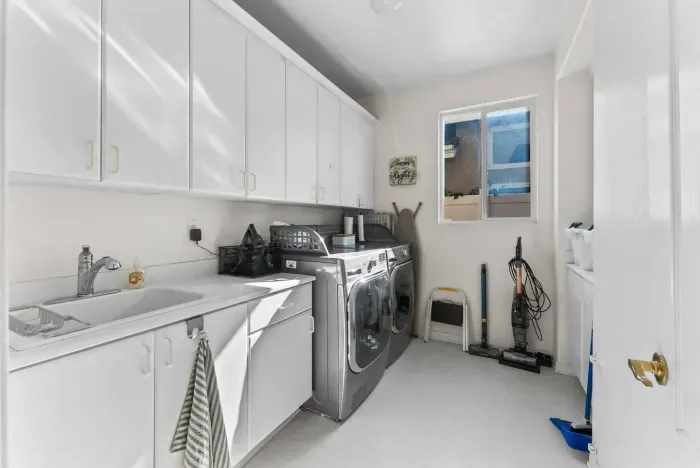 Laundry room gleaming with chrome appliances and clean white cabinetry