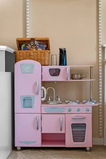 Vintage pink play kitchen stocked with baskets and tinware