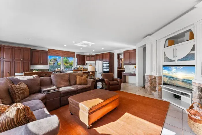 Plush living room opens to kitchen, wrapped in golden wood tones
