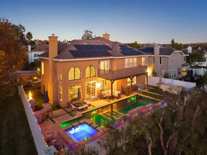 Pool glows at dusk beside the sunlit patio and outdoor lounge