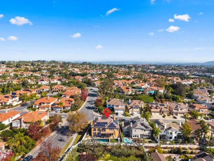 Red pin marks home among sunlit suburban rooftops