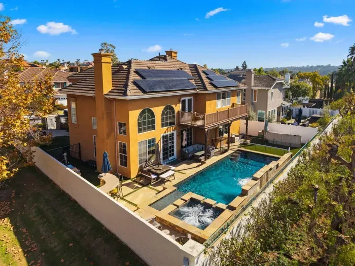 Backyard pool framed by tall walls and solar panels above