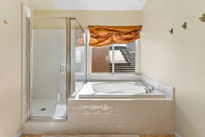Deep soaking tub beneath a bronze-tinted window curtain