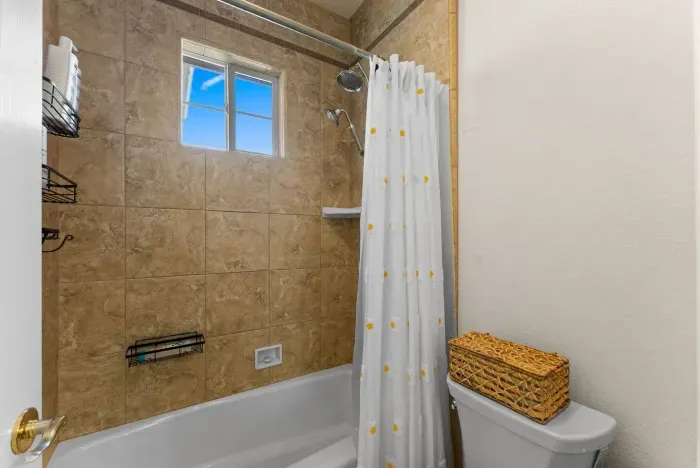 Sunlight hits tiled walls beside a crisp white shower curtain