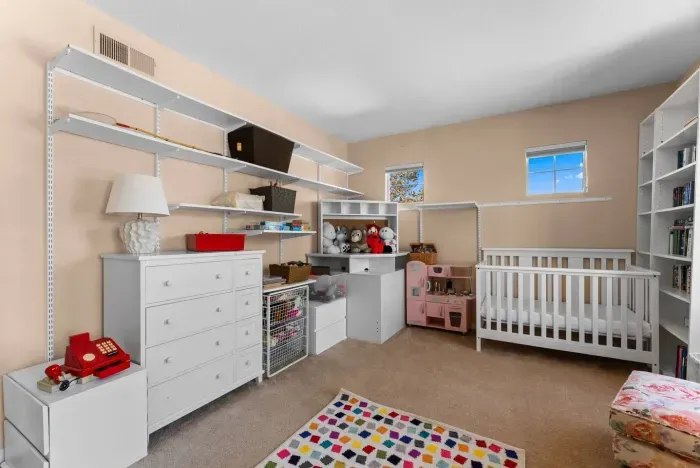 Children’s room lined with shelves, crib, and bright rug dots