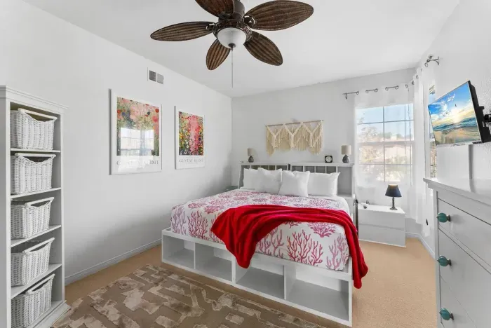 Bright bedroom accented by red throws and floral art