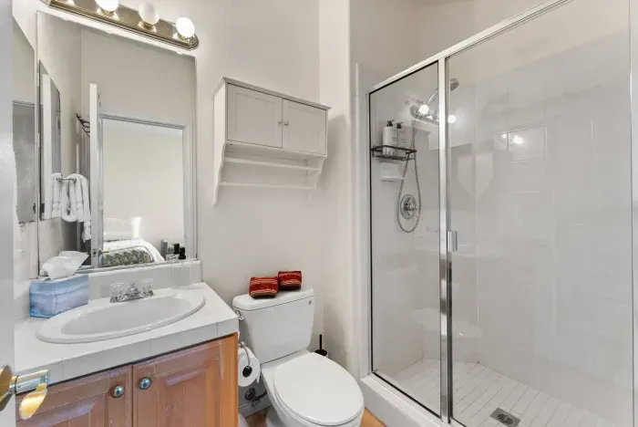 White-tiled bath with glass shower and compact vanity