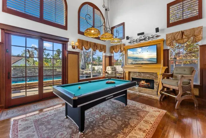 High ceilings frame a cozy billiard room with warm firelight