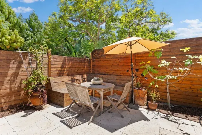 Sunny private patio with lush greenery and a shaded dining spot—perfect for morning coffee or evening meals outdoors.
