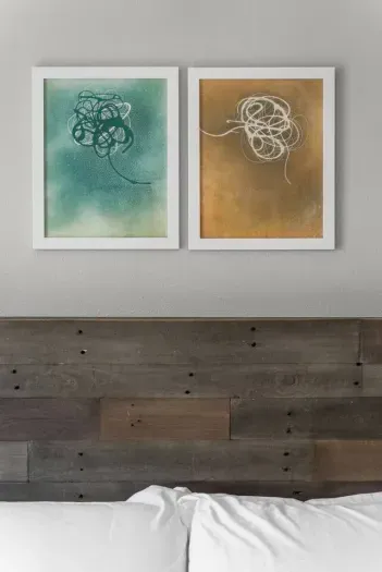 Minimalist coastal art and a rustic wood headboard create a serene, stylish bedroom retreat.