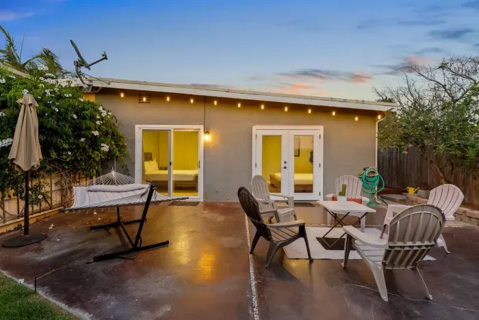 Spacious backyard patio with fire pit, hammock, and string lights—perfect for sunset lounging and starlit gatherings.