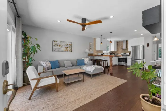 Bright open living space with modern coastal décor, comfy seating, and seamless flow into the kitchen and patio.