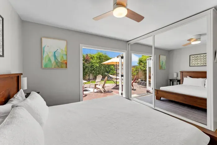 Bright king bedroom with mirrored closets and direct access to a private patio—indoor comfort meets outdoor relaxation.