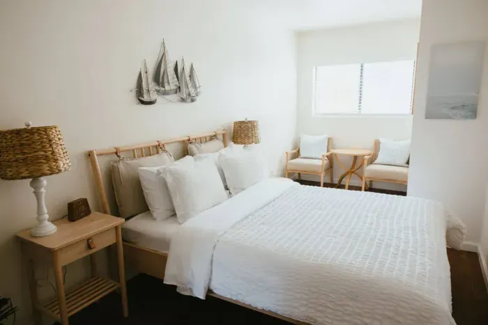 Airy bedroom with white bedding and natural wood furniture.