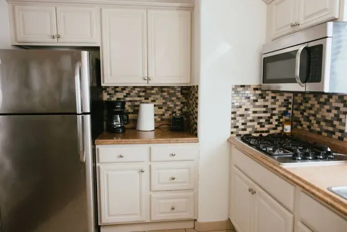 Clean kitchen with stainless appliances and mosaic backsplash.