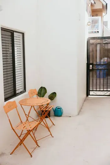Cozy outdoor nook with orange bistro set and potted plants.