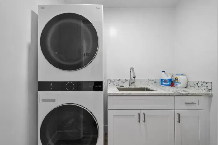 Modern laundry room with stacked washer-dryer and sleek marble countertop.